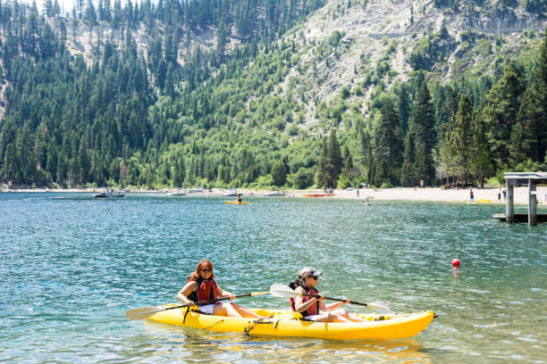 Two female friends row in a dual kayak on Lake Tahoe in Emerald Bay. Concept for teamwork, female friendship, working togethe stock photo