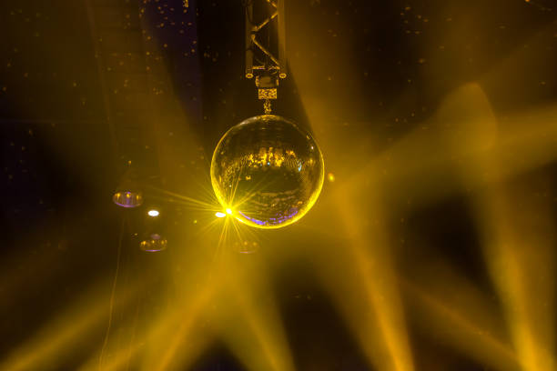 Disco ball ornament reflecting yellow/gold light.