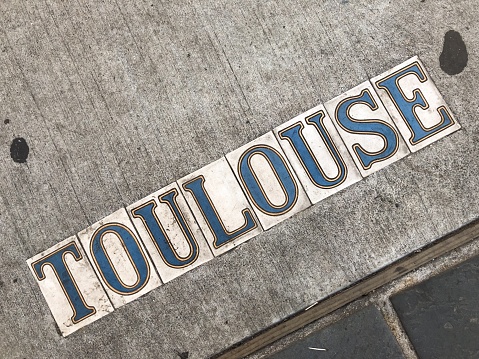Sidewalk street sign tiles in New Orleans French Quarter.