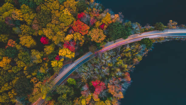 Aerea view in the autumn of the road with passing cars Aerial view in the autumn of the road with cars passing in long exposure, photo made with drone. blue ridge parkway stock pictures, royalty-free photos & images
