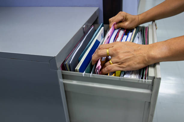 istock Hand of Man Search files document in a file cabinet in work office 1060712824