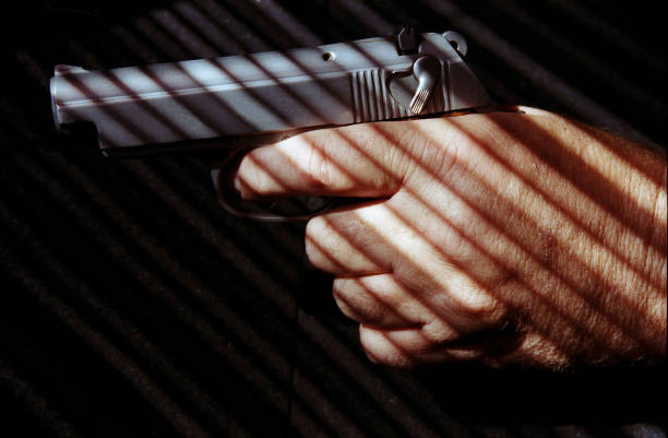 istock Senior man holds handgun in hand.  Light and shadows.  Dark background. 1060712968