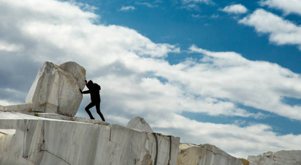 A small black figure pushing a large marble stone. heavy tasks and problems concept. Sisyphean work, task.