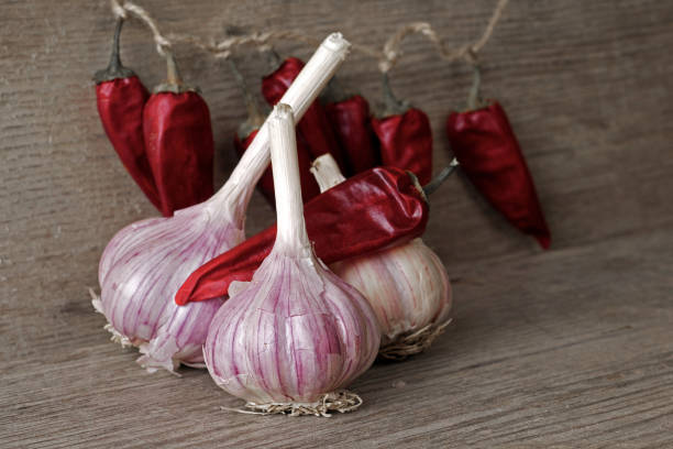bulbos de ajo y chiles secos en una tabla de madera - garlic hanging string vegetable fotografías e imágenes de stock