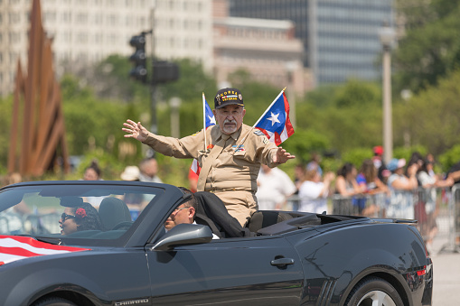 Chicago, Illinois, USA - June 16, 2018: The Puerto Rican Day Parade, Puerto Rican Korea war veteran carrying the puerto rican flags, waving at spectators
