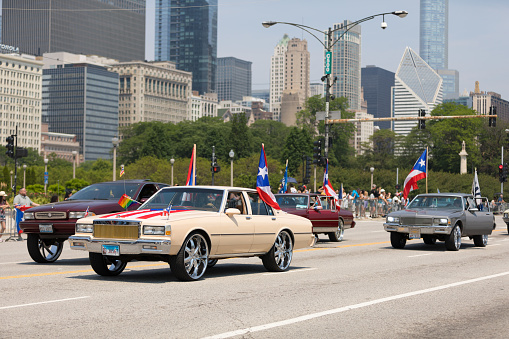 Chicago, Illinois, USA - June 16, 2018: The Puerto Rican Day Parade, Cars Donk modified carrying puerto rican flags down the street during the parade