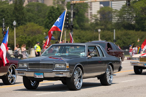 Chicago, Illinois, USA - June 16, 2018: The Puerto Rican Day Parade, Cars Donk modified carrying puerto rican flags down the street during the parade