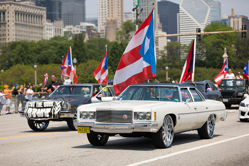 Chicago, Illinois, USA - June 16, 2018: The Puerto Rican Day Parade, Chevrolet Cars Donk modified carrying puerto rican flags down the street during the parade