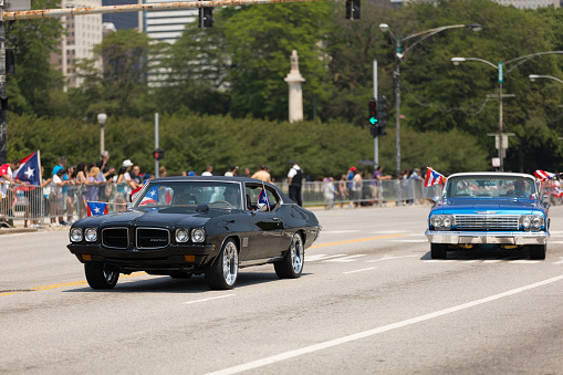 Chicago, Illinois, USA - June 16, 2018: The Puerto Rican Day Parade, Puerto RIcan driving a Pontiac GTO Black Classic car with puerto rican flags during the parade