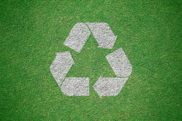 istock White recycle logo painted on green grass field from top view. Recycling concept 1060736404