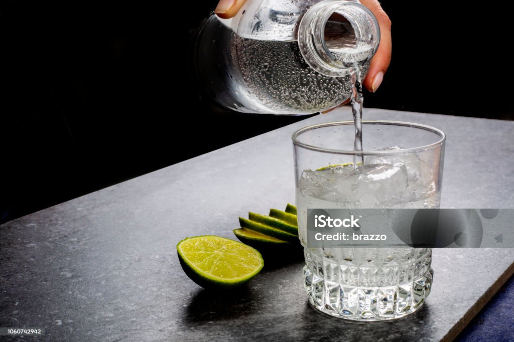 Water being poured into a glass Water being poured into a glass next to sliced lime Water Stock Photo