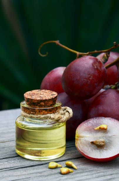 Grape seed oil in a glass jar and fresh grapes on old wooden table in the garden.Spa,bodycare,Bio,Eco products concept. stock photo