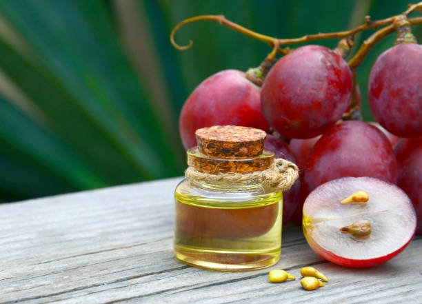 Grape seed oil in a glass jar and fresh grapes on old wooden table in the garden.Spa,Bio,Eco products concept. stock photo