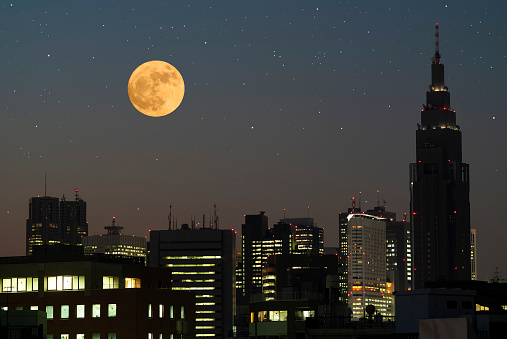 Full moon rising over the Tokyo Shinjuku skyline with copy space.