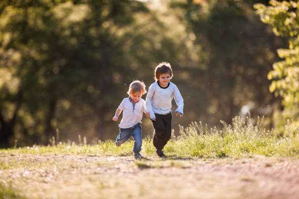 istock Two happy small boys running together in the park. 1060764972