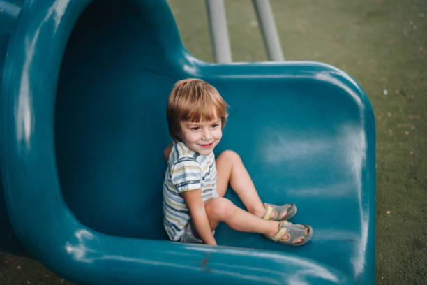 istock Cute smiling boy sitting on a slide at the playground. 1060766374