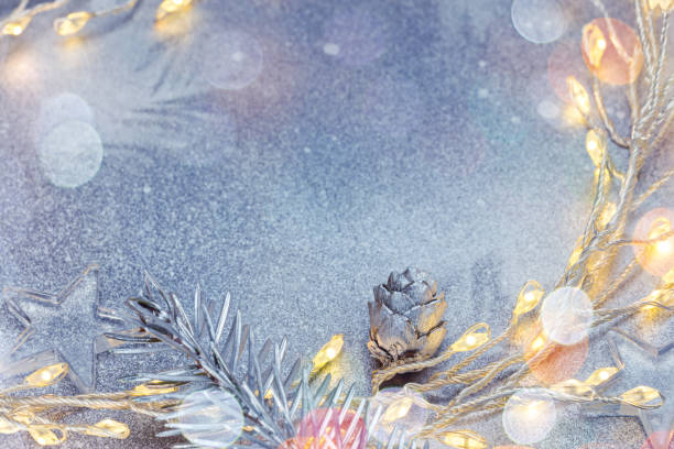 istock christmas lights and fir tree branch with decorations on silver winter background 1060766388