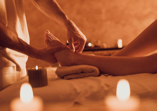 terapista irriconoscibile che massaggia il piede del cliente presso la spa sanitaria. - foot massage foto e immagini stock
