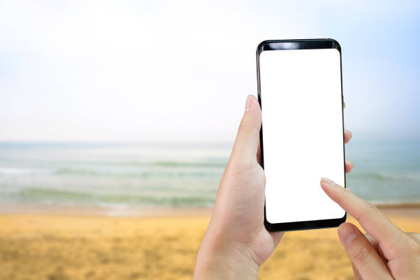 istock Hands using mockup smartphone with sea beach view on background. 1060775058