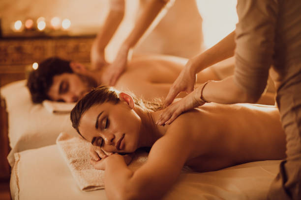 Young couple having relaxing back massage at beauty spa. Young couple having back massage during their spa treatment. spa massage stock pictures, royalty-free photos & images