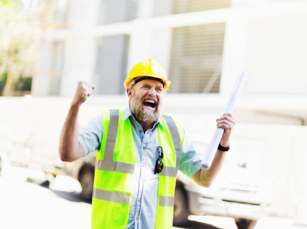 istock Grimacing construction worker holding blueprints shakes fists angrily 1060775342