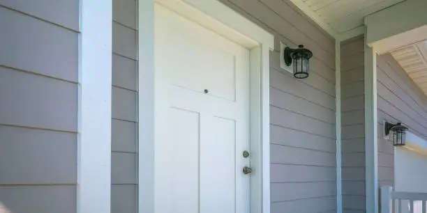 Photo of Front door of a home with a lamp on the gray wall