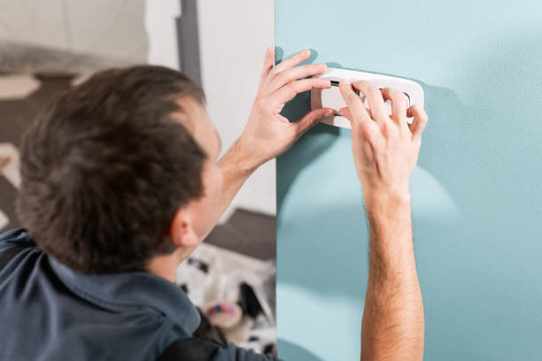 istock Electrician worker installs light switch and socket on wall in room. Screwdriver, close-up electrician hands. 1060777512