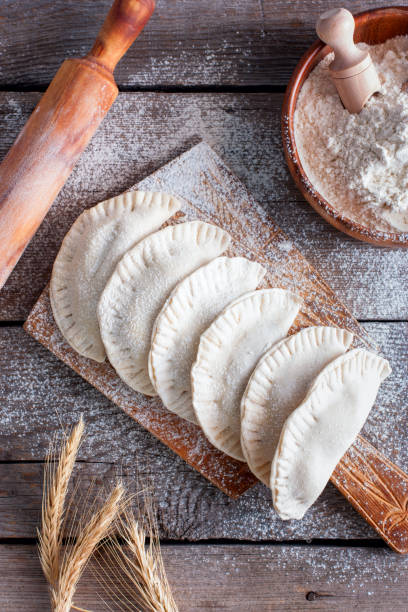 istock Raw chebureks on a wooden board, top view, selective focus 1060782592