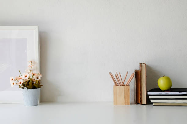 istock Workspace flower pot, pencil, books and photo frame on white table. 1060782888
