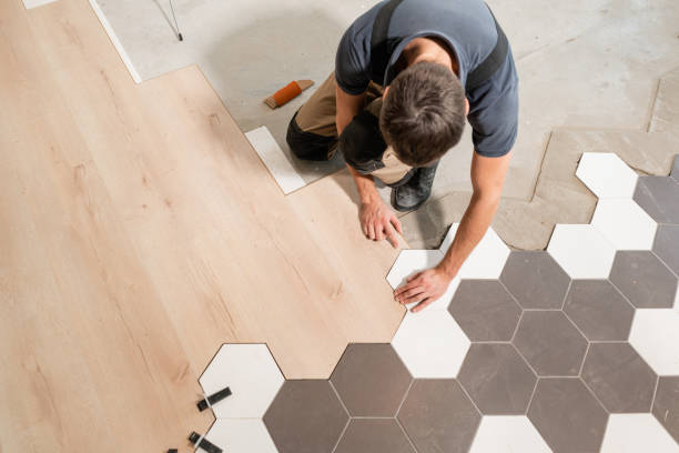 mannelijke werknemer installeren nieuwe houten gelamineerde bevloering. de combinatie van houten panelen van laminaat en keramische tegels in de vorm van honingraat. keuken renovatie. - werkvloer stockfoto's en -beelden