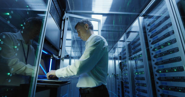 technicien travaille sur un ordinateur portable dans un data center - network server rack computer mainframe photos et images de collection