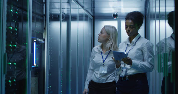 istock Two women are working in a data center with rows of server racks 1060784890
