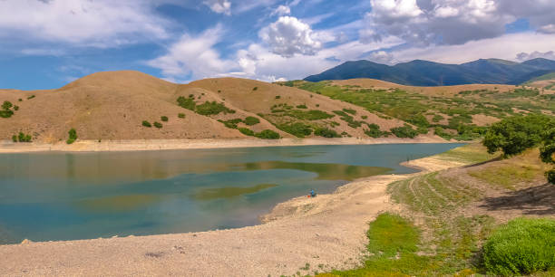Reservoir at Settlement Canyon in Tooele Utah Reservoir at Settlement Canyon in Tooele Utah. Scenic view of Settlement Canyon Reservoir with a lake for fishing beside hills in Tooele, Utah. Overhead is a blue sky with illuminated white clouds. tooele stock pictures, royalty-free photos & images
