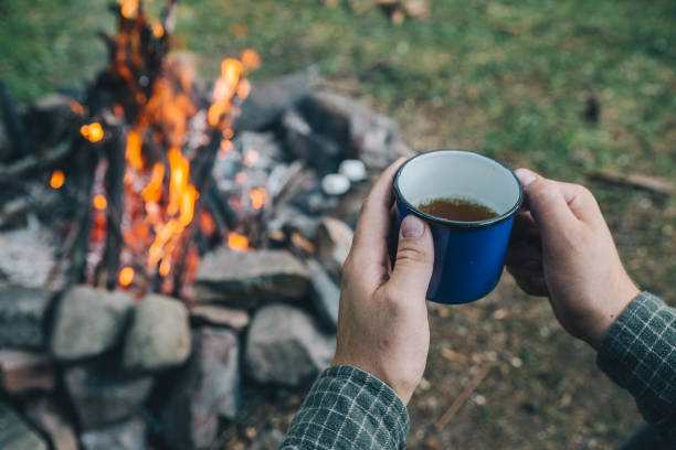 istock first point of view. man drinking tea in metal cup near camp fire 1060798332