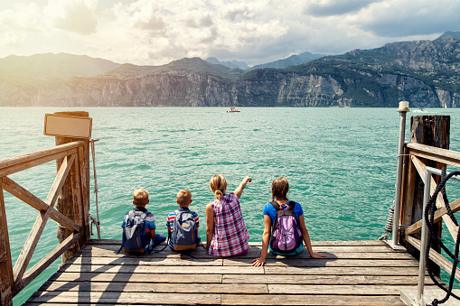 Family enjoying Garda Lake vacations. They are sitting on pier in Malcesine and enjoying view of Lake Garda.\nNikon D850