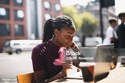 istock Woman with braids using a laptop at an outdoor cafe 1060801268