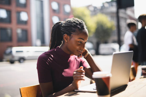 Woman with braids using a laptop at an outdoor cafe Woman with braids using a laptop at an outdoor cafe braided hair photos stock pictures, royalty-free photos & images