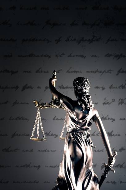 Statue of lady justice in front of a handwritten document.