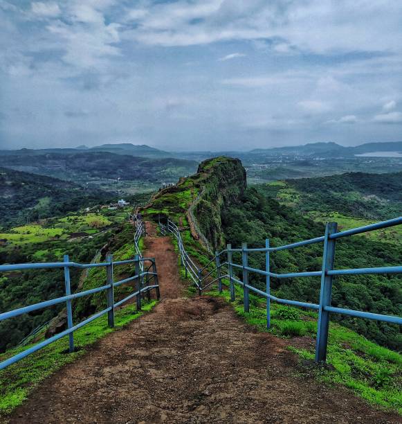 A grid on the fort Lohgad is an old fort near Pune, Maharashtra , India. There is Edge of the Mountain called "Vinchukata" there was a blue grid railing on it , it looks  just an awesome in monsoon. pune photos stock pictures, royalty-free photos & images