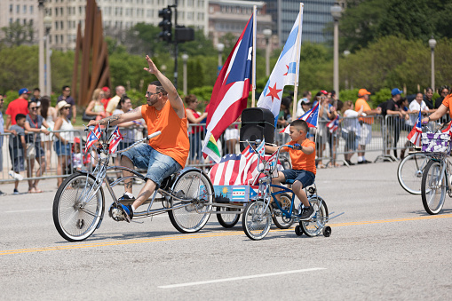 Chicago, Illinois, USA - June 16, 2018: The Puerto Rican Day Parade, Members of the Classic Cruisers Bicycle Club riding a bicycles with the puerto rican flag, riding down the street during the parade