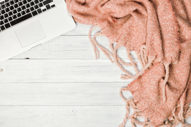 istock Home office desktop with a laptop, cozy warm pink plaid. 1060809576