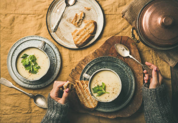 zupa z kremu selera w kubkach i kobiece ręce w swetrze - hot lunch zdjęcia i obrazy z banku zdjęć