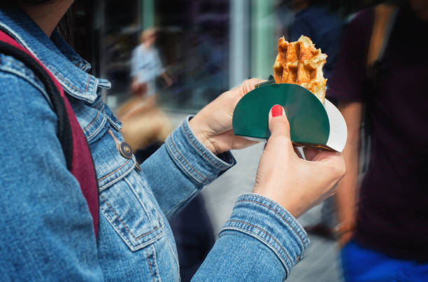 wafle belga tradicional en manos de la mujer en una calle. - brussels waffle belgian waffle people fotografías e imágenes de stock