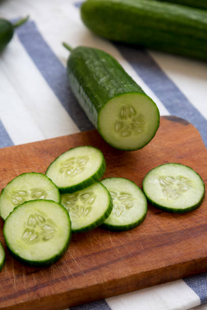 istock Chopped raw organic green cucumbers on rustic wooden board, side view. Close-up. 1060823042