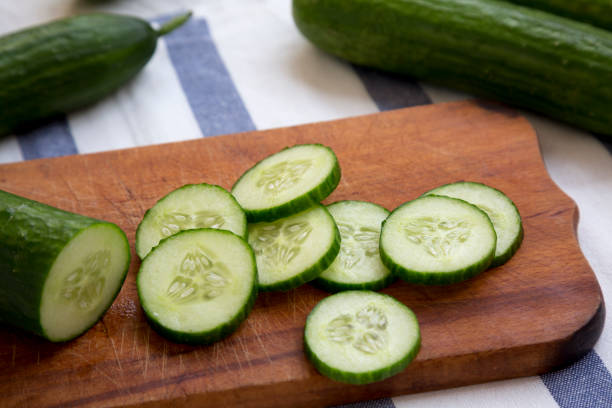 istock Sliced raw organic green cucumbers on rustic wooden board, side view. Closeup. 1060823122