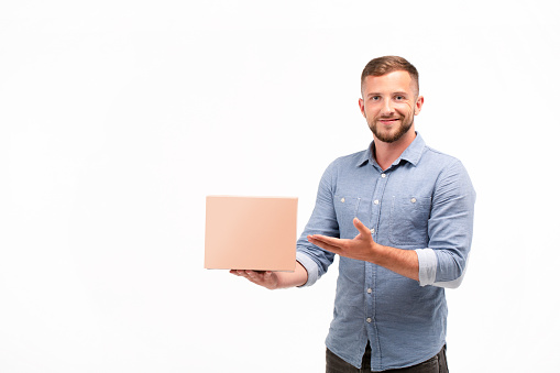 Casual young man holding a box isolated on a white background. Copy space