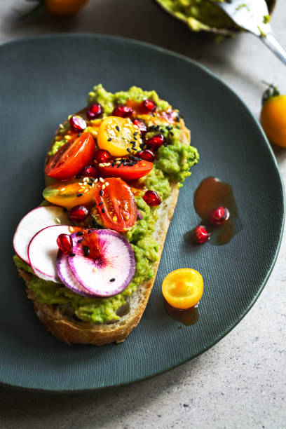 istock Mashed Avocado with Cherry Tomato, Radish,  Pomegranate, Sesame on toast with Chili sauce 1060830922