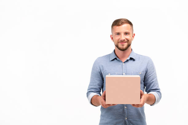 Casual young man holding a box isolated on a white background Casual young man holding a box isolated on a white background. Copy space Holding stock pictures, royalty-free photos & images