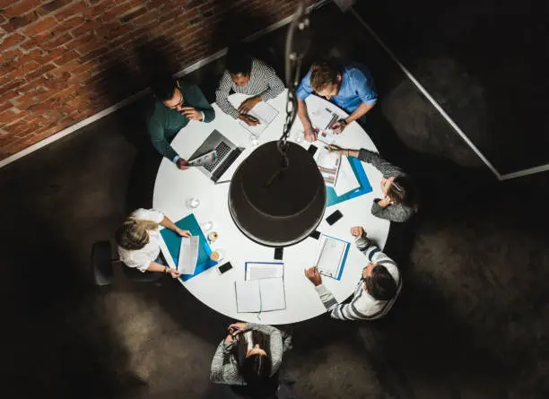 Photo of Above view of business colleagues analyzing reports on a meeting at the table.