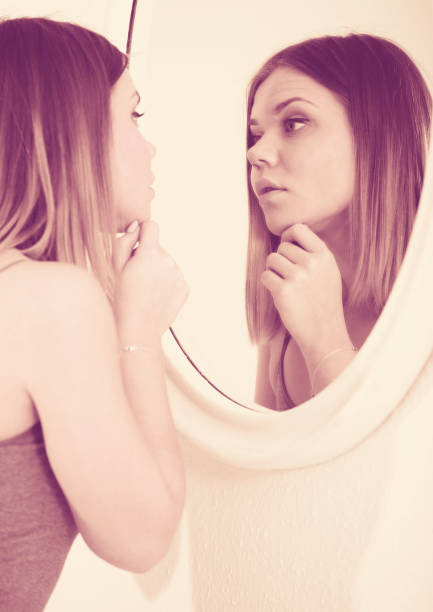 istock Young woman using mirror and touching face in bedroom 1060831834